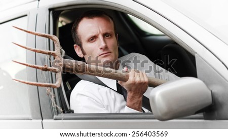 Aggressive businessman driver, with a fork inside the car.