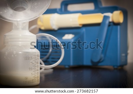 Close up on a old breast pump with a bottle filled with breast milk .A breast pump is a mechanical device that extracts milk from the breasts of a lactating woman.
