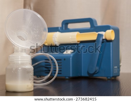 Close up on a old breast pump with a bottle filled with breast milk .A breast pump is a mechanical device that extracts milk from the breasts of a lactating woman.