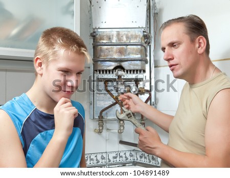 The father and the son-teenager together in  repair a gas water heater.