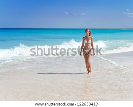 Young graceful woman goes on coast of ocean