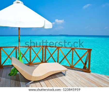 Parasol and chaise lounges on a terrace of water villa, Maldives.