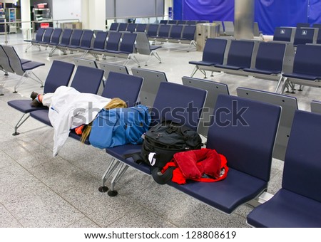Passenger sleeps on seats in an empty night airport after flight cancellation