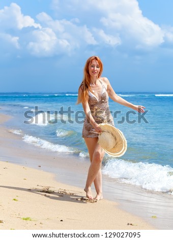 Young  woman goes on ocean coast  with hat