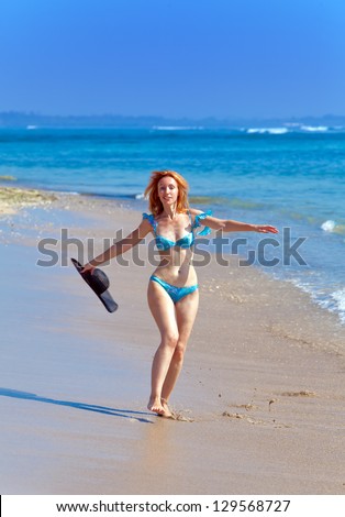 Young  woman goes on ocean coast  with hat