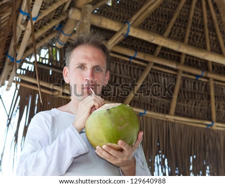 attractive man drinks coconut juice from a nut