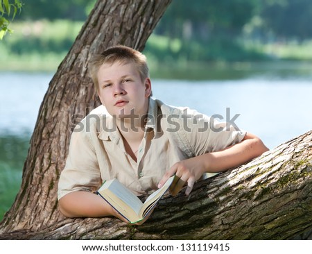 Young guy prepare for lessons, examination in spring park near lake