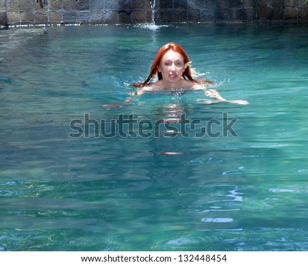 The young beautiful woman swims in pool