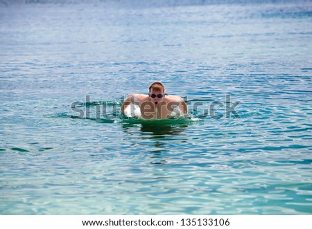 young sporting man swims in the sea dolphin style.