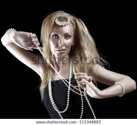 beautiful young blonde woman with long hair and a pearl beads on dark background.