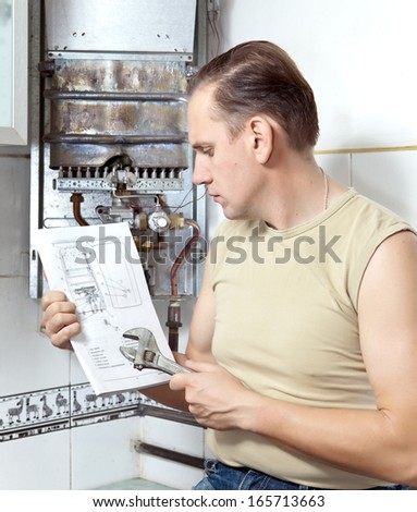The man looks the instruction on repair a gas water heater.