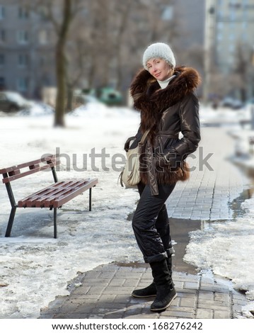 The young woman in a jacket with a fur collar on the street in the winter