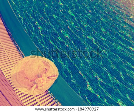 The straw hat lies on the brink of pool,with a retro effect