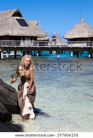 The young beautiful woman in a romantic dress with a rose  at the sea edge