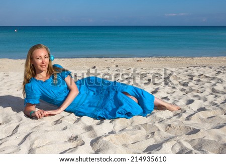 The young woman in a romantic dress lies on sand near the sea, Cuba, Varadero