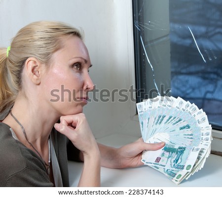 The housewife upset and counts money for repair of a window which has burst in a frost
