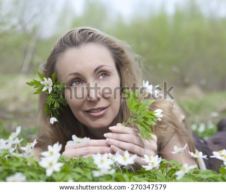 The young beautiful woman in the field of blossoming snowdrops in the early spring