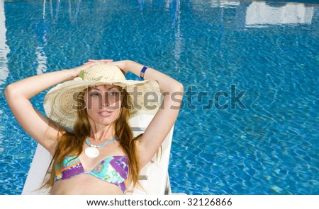 Woman smiles in straw hat having a rest at pool