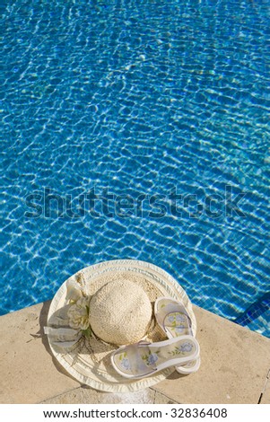 The straw hat and slippers lies on the brink of pool