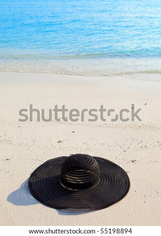 Black millinery  from sun lays on sand before ocean