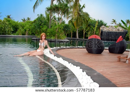 Young pretty woman in pool in tropical garden