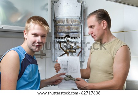 The concept of relations in a family. The father and the son-teenager together look the instruction on repair a gas water heater.