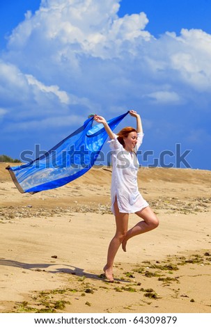 Young graceful woman  in white tunic with cape in hands  on coast of ocean