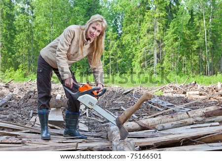 The young woman in wood saws a tree a chain saw