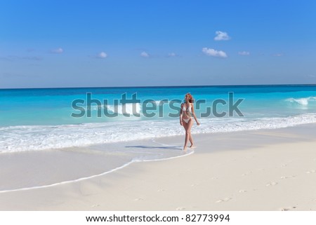 The young woman goes on a beach at sea edge