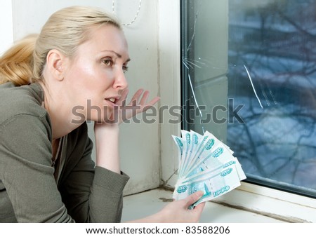 The housewife cries and counts money for repair of a double-glazed window which has burst in a frost