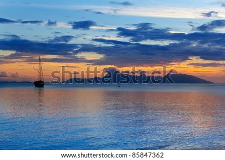 A sunset over ocean and  silhouette of boat and Orohena mountain. Polynesia. Tahiti.