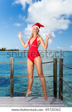 The woman in New Year\'s Santa-Klaus cap jumping on background of ocean