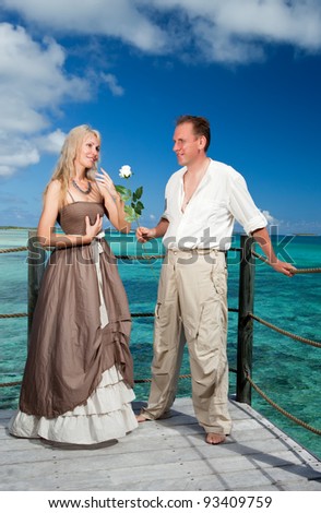 man gives a rose to the woman on the turquoise sea background