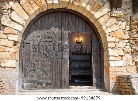 Semicircular wooden door with metal finishing in a stone wall.