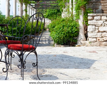 shod chairs on the stone avenue, in a surrounding of green branches