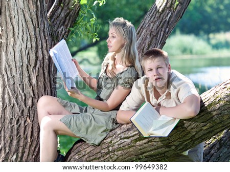 Young guy and the girl prepare for lessons, examination in spring park