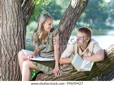 Young guy and girl with books on the nature near lake