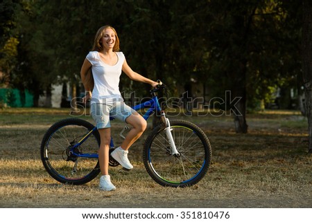 Urban biking - smiling teenage girl with bike in the city park