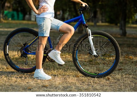 Urban biking - smiling teenage girl with bike in the city park