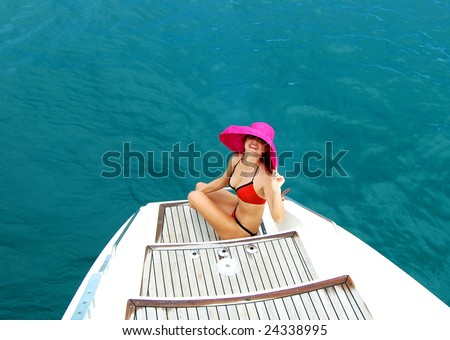 Beautiful woman with a red hat over blue ocean on a catamaran