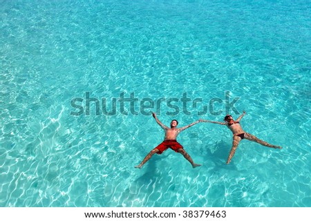 Young happy couple floating in the turquoise ocean