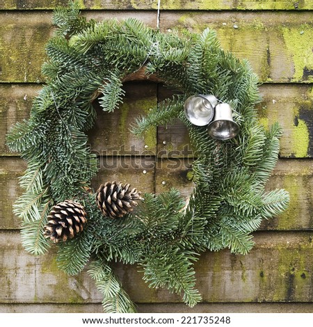 Square image of a Christmas wreath with silver bells and two pine apples
