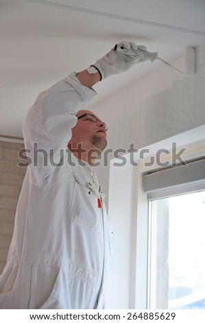 Home decorator painting a wall white with a roller