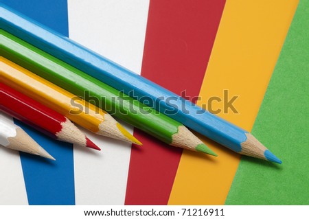 Five different colored pencils on different colored pieces of paper