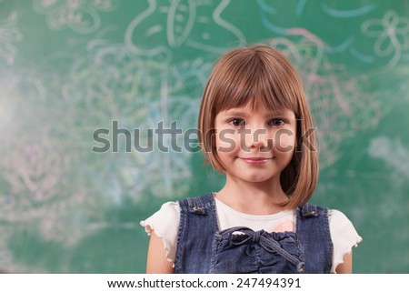 Portrait of girl standing in front off drawn chalkboard in elementary school