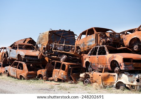 Stack of damaged rusted car scraps on junkyard