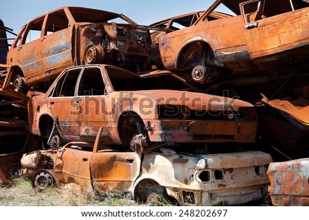 Stack of damaged rusted car scraps on junkyard