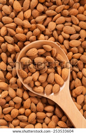 Almond background with large spoon full with fruits. Raw organic food full of good nutrients.