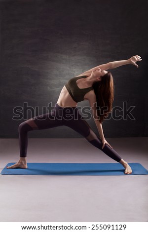 Woman practicing yoga in Reverse Warrior pose. Studio shoot