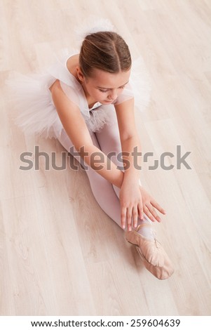 Little girl ballerina stretching and dancing on the floor of ballet studio